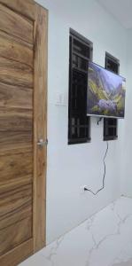 telewizor z płaskim ekranem na ścianie obok drzwi w obiekcie MaNelly Guest House Hotel w mieście Donsol
