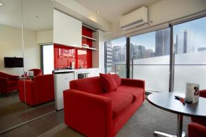 un soggiorno con divano rosso e una cucina di City Edge on Elizabeth Apartment Hotel a Melbourne