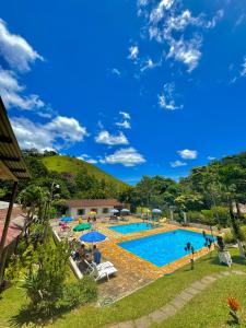 uma grande piscina com pessoas sentadas à sua volta em Hotel Fazenda Rancho Mineiro em Engenheiro Paulo de Frontin