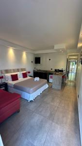 1 dormitorio con 1 cama grande y 1 sofá rojo en Ayres Village Apart en Pinamar