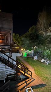 a deck with a table and chairs in a yard at night at Ayres Village Apart in Pinamar