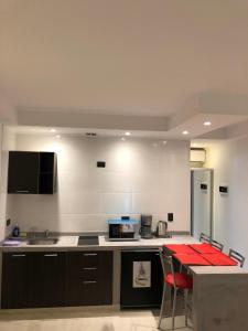 a kitchen with a counter and a red table in it at Ayres Village Apart in Pinamar