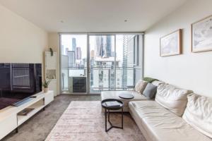 uma sala de estar com um sofá e uma grande janela em Spencer St Serenity Stylish 1-Bedroom Apartment Escape em Melbourne