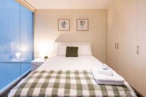 um quarto com uma cama grande e um cobertor xadrez em Spencer St Serenity Stylish 1-Bedroom Apartment Escape em Melbourne