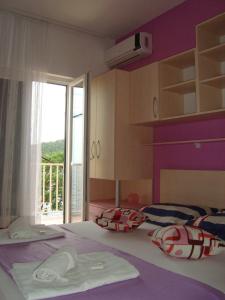 a bedroom with a bed with pillows and a window at Apartments Kiro in Milna