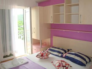 a bedroom with purple walls and a bed with towels at Apartments Kiro in Milna