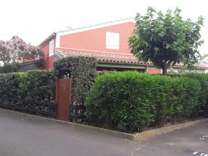 a building with a fence and some bushes and a tree at Maison Vendres, 3 pièces, 4 personnes - FR-1-701-82 in Vendres