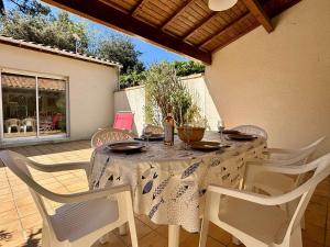 a table with white chairs and a white table cloth at Maison 6 couchages à Oléron - Proche mer, jardin clos, WiFi, animaux admis, ménage inclus - FR-1-246A-299 in Saint-Georges-dʼOléron