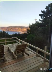 una terraza de madera con 2 sillas en la parte superior. en Vista Hermosa Laguna Verde, en Laguna Verde