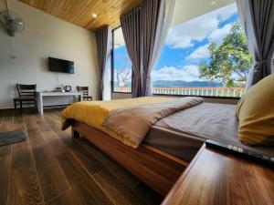 a bedroom with a large bed with a large window at Khu Nghỉ Dưỡng View Triệu Mây in Lam Ha