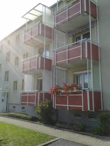 バート・ベルカにあるApartment Ilmtal Jenaの赤いバルコニーと花が飾られたアパートメントビル