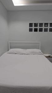 a white bed in a white room with a white bedspread at MaNelly Guest House Hotel in Donsol