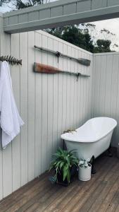 a bath tub sitting on a deck next to a wall at Driftwood Rest Binalong Bay Sleeps 4 in Binalong Bay