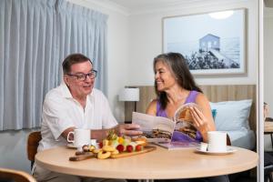 un homme et une femme assis à une table dans l'établissement Southport Motel & Apartments, à Gold Coast