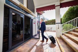 ゴールドコーストにあるSouthport Motel & Apartmentsのスーツケースを持って出て行く男
