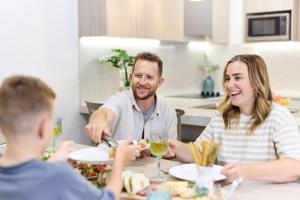 ゴールドコーストにあるSouthport Motel & Apartmentsの食卓に座って食べ物を食べる男女