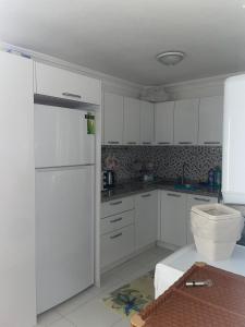 La cuisine est équipée de placards blancs et d'un réfrigérateur blanc. dans l'établissement Osman gazi, à Samandra