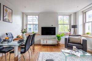 a living room with a table and chairs and a television at Central Fitzrovia - CityApartmentStay in London
