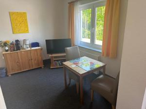 ein Wohnzimmer mit einem Tisch und einem TV in der Unterkunft Die kleine Pension in Delmenhorst