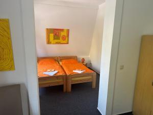 um pequeno quarto com uma cama com lençóis laranja em Die kleine Pension em Delmenhorst