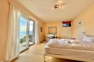 a bedroom with a bed and a large window at Peace Over The Lake Rooms - Happy Rentals in Brissago
