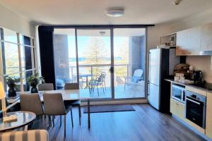 a kitchen with a table and a dining room with a view at Apartment at The Entrance in The Entrance +5 photos