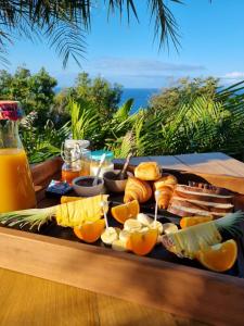 ein Tablett mit Lebensmitteln auf einem Tisch mit Orangen und anderen Lebensmitteln in der Unterkunft Maison d'hôtes Villa des Mascareignes in Petite Île