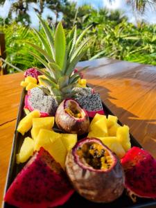 a plate of fruit on a table with a pineapple at Maison d'hôtes Villa des Mascareignes in Petite Île