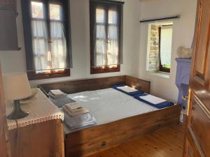 uma cama grande num quarto com duas janelas em Traditional house em Nikiti