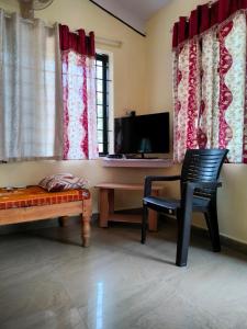 a living room with a desk and a chair and a television at White bungalow in Madikeri