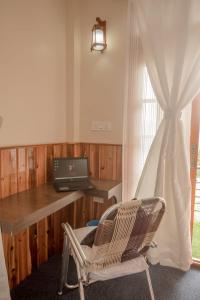 a desk with a laptop and a chair next to a window at Kutumba Kutir in Mirik