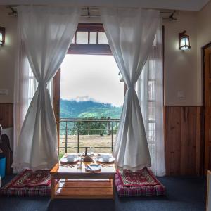 a room with a table and a large window at Kutumba Kutir in Mirik