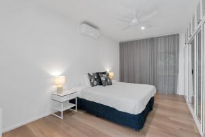 a white bedroom with a bed and two lamps at Ohana Palm Cove in Palm Cove +48 photos