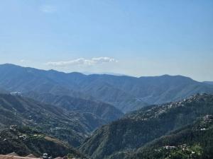 a view of a mountain valley with trees and houses at Cozy Cove - Newly built 3BHK Duplex with rare valley view in Shimla