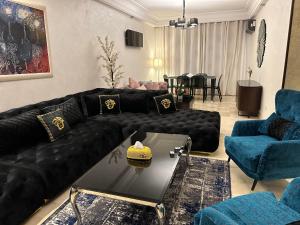 - un salon avec un canapé en cuir noir et des fauteuils bleus dans l'établissement Appartement à Casablanca de luxe, à Casablanca