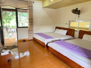 - une chambre avec 2 lits, un ventilateur et une fenêtre dans l'établissement Cô Tô Lương Chi, à Quảng Ninh