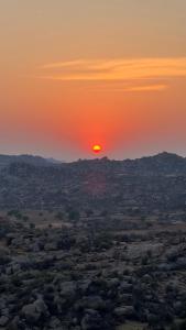 a sunset in the desert with the sun in the sky at Jungle Tree Hostel Hampi in Hampi