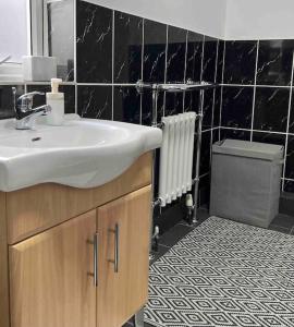 a bathroom with a sink and a black tiled wall at King-size bed en- suit, Luxury refurbished home in Balderton