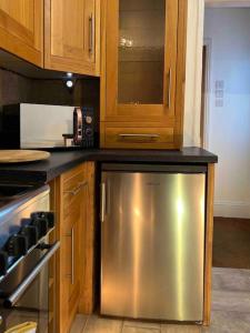 a kitchen with a stainless steel refrigerator and wooden cabinets at King-size bed en- suit, Luxury refurbished home in Balderton