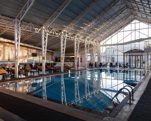 una grande piscina con tavoli e sedie in un edificio di Jannat Resort Osh a Oš