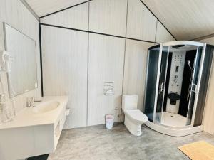 a bathroom with a glass shower and a toilet at Koppie Inn in Xiaoliuqiu