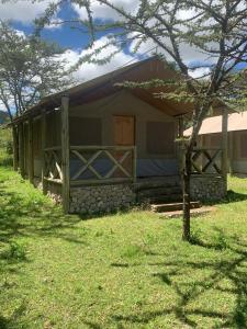 ein kleines Haus mit einem Holztor auf einem Feld in der Unterkunft Eco mara forest camp in Ololaimutiek