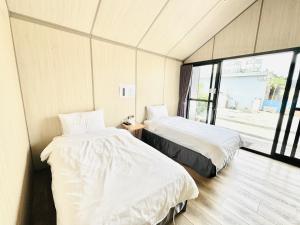 2 camas en una habitación con ventana en Koppie Inn en Xiaoliuqiu