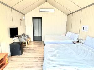 Zimmer mit 2 Betten und einem TV. in der Unterkunft Koppie Inn in Xiaoliuqiu
