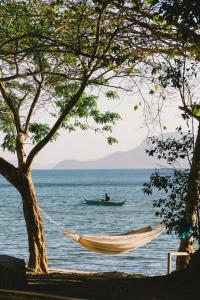 een hangmat op het strand met een man in een boot in het water bij Parada Beach Camp in El Nido