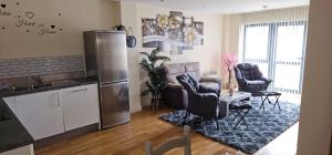 eine Küche und ein Wohnzimmer mit einem Kühlschrank und Stühlen in der Unterkunft Spacious 2BDR Flat for 5 in City Centre in Liverpool