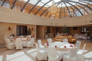 Habitación grande con mesas, sillas y lámpara de araña. en Jannat Resort Osh, en Osh
