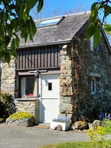 a stone cottage with a white garage door at The Cosy Pad Glan Y Morfa Bach in Tywyn +12 photos