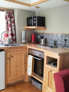 a kitchen with wooden cabinets and a stove top oven at The Cosy Pad Glan Y Morfa Bach in Tywyn +12 photos