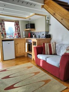 a living room with a red couch in a kitchen at The Cosy Pad Glan Y Morfa Bach in Tywyn